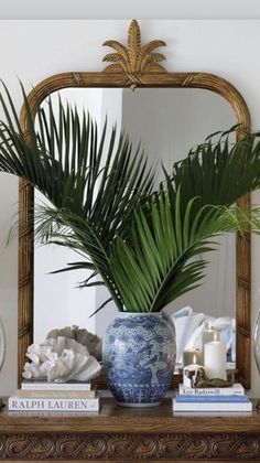 a mirror sitting above a vase filled with palm leaves