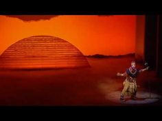 the man is dancing in front of an orange sky with clouds and pyramids on it