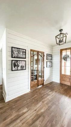 an empty living room with wood floors and pictures on the wall above the doorways