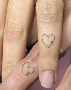 two people with tattoos on their fingers and one has the letter e written on it