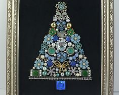 a christmas tree made out of beads and other items in a gold frame on a table