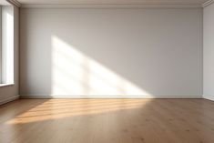 an empty room with white walls and wooden floors, sunlight shining through the window onto the floor