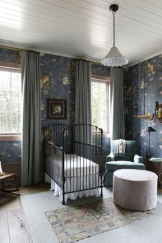 a bedroom with floral wallpaper and a metal crib in the corner next to a window