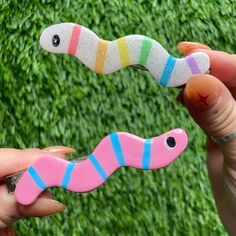 a hand holding a pink and blue toy worm