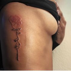 a woman with a rose tattoo on her lower back and side ribs, showing the outline of a flower