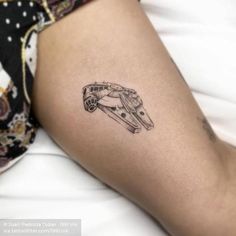 a woman's leg with a small tattoo of a ship on the back of her thigh