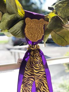 a purple and gold ribbon with a tiger print on it hanging from a window sill