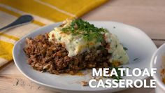 meatloaf casserole on a white plate next to a bowl of soup