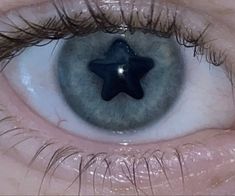 an eye with a blue star in the middle of it's iris area, and long eyelashes