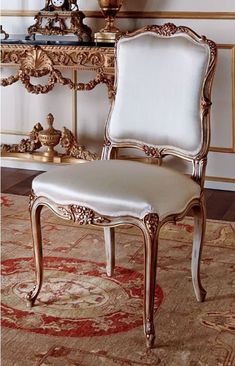 a white chair sitting on top of a rug next to a table with a mirror