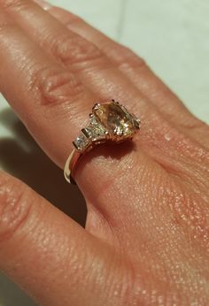 a person's hand with a ring on top of it and an orange diamond in the middle