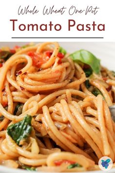 a plate of pasta with spinach and tomatoes on it, text overlay reads whole wheat one pot tomato pasta