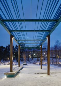 a covered walkway with benches and lights in the snow at night, under a blue sky