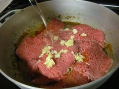 meat being cooked in a pot on the stove with a spatula sticking out of it