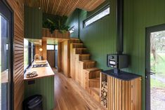 the interior of a house with green walls and wooden stairs leading up to an open floor plan