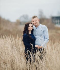 a man and woman are standing in the tall grass with their arms around each other