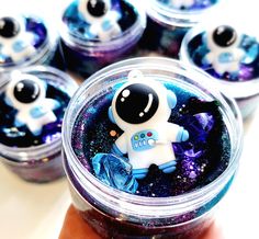 a hand holding a jar filled with blue and purple glittered space themed candies