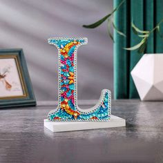 the letter j is decorated with multicolored beads and bead work on it