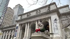 a statue of a dog on top of a pillar in front of a large building