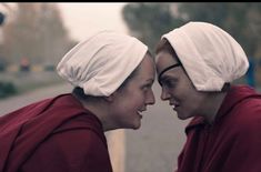 two women wearing white head coverings on their heads are looking into each other's eyes