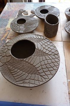 three vases sitting on top of a wooden table next to cups and saucers