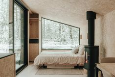 a bed sitting next to a window in a room filled with furniture and snow covered trees