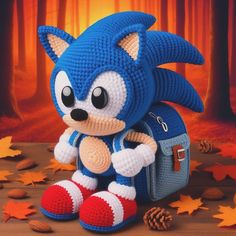 a crocheted sonic the hedgehog doll sitting on top of a pile of leaves