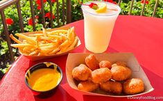 a red table with some food and a drink sitting on top of it next to a bowl of fries