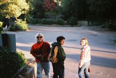 three people are standing on the side walk