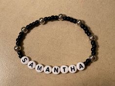 "Stretchy name bracelet measures 7 1/8\" and reads SAMANTHA in white plastic alphabet beads with black letters. 7 round shiny 6mm silver tone beads add visual interest to 28 black 4mm seed beads on this stretchy NAME bracelet.  This can be made in a wide variety of color combinations, bead types, and sizes. Any name or word(s) and then listed for you to purchase. *Special orders made and mailed in one business day. Watch for more one of a kind ideas from my imagination, or opt to design your own Word Bracelet, Alphabet Beads, Custom Bracelet, My Imagination, Stretchy Bracelets, Name Bracelet, Black Letter, Lovely Earrings, Hamsa Hand