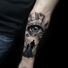 a man's arm with a clock and an eye tattoo on the left forearm