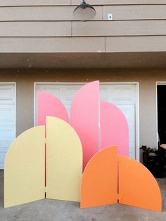 three different colored paper shapes in front of a garage with two doors and one door open