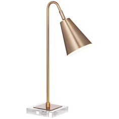 a brass colored lamp on a clear base with a white light behind it and an acrylic block underneath