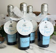 three bottles of wine with tags on them sitting in front of flowers and other items