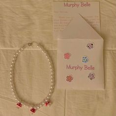 a bracelet with charms and a card on a white tablecloth next to the package