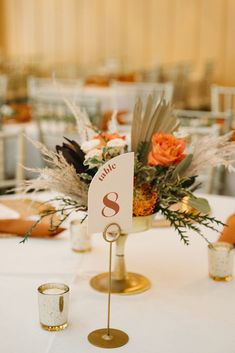 the table is set up for a wedding reception with white linens and gold place cards