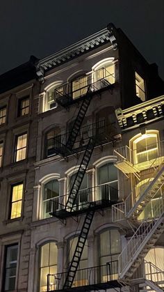 a fire escape is lit up at night in front of an apartment building with stairs leading to the second floor