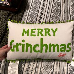 someone is holding a pillow that says merry grinmas on the front and green lettering on the back