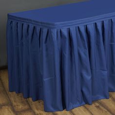 a blue bed skirt sitting on top of a wooden floor