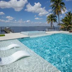 an empty swimming pool next to the water with palm trees in the background on a sunny day