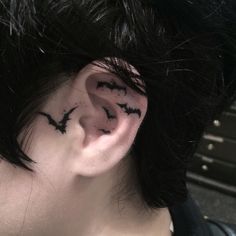 a man with black ink on his ear has bats painted on the side of his ears