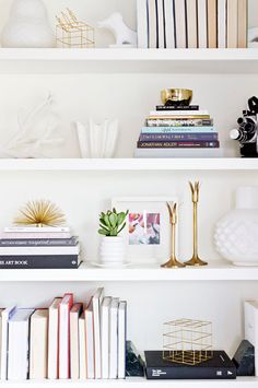 white shelves with books, vases and pictures on them