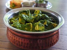 a bowl filled with green food on top of a wooden table