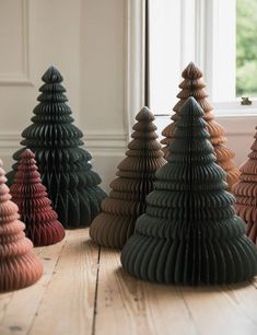 there are many small wooden christmas trees on the floor in front of a window with white trim