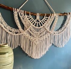 macrame hanging on the wall next to a vase