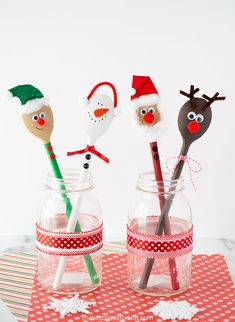 three glass jars filled with christmas decorations and paper santa hats on top of each other