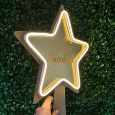 a person holding up a star shaped sign with the words feliz navidad written on it