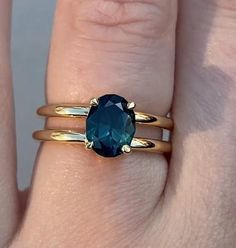 a woman's hand with two gold rings and an oval blue stone on it