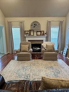 a living room with couches, chairs and a fire place in the middle of it