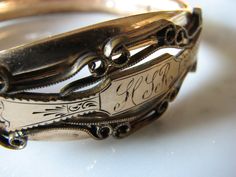 "This exquisitely ornate bangle is an elegant piece of history.  The inside is marked \"Gold Shell, 12 K, MH & Co.\"  Both hinge and clasp are in good condition, as is the surface ornamentation and the monogram (H S R - although the middle initial is in question.)  The width of the bangle is just under .5 inches (1.1 cm) wide, although it increases to .75 inches (2 cm) in the front at the widest point. The inner circumference is 7.5 inches (19 cm). There is wear on the edges, consistent with the Luxury Victorian Etched Bangle, Surface Ornamentation, Saint Paul, Early 1900s, Red Nails, Bangle Bracelet, Hinges, Mother Of Pearl, Gold Filled